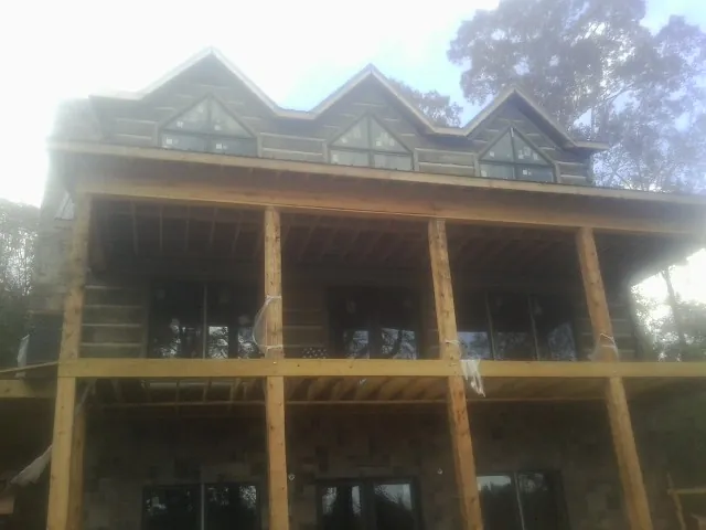 Dormers and porch framing on a large log home under construction — Roof Coating work by our crew in Rock City Falls