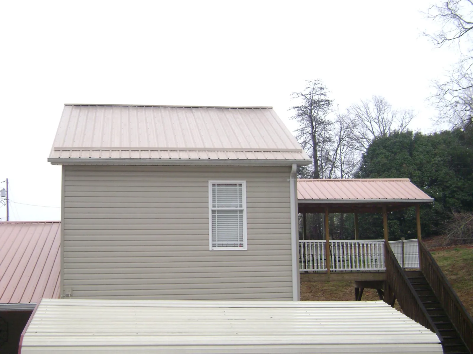 Tan metal roofs on a two story addition and attached porch, from a Roof Replacement job in Rock City Falls