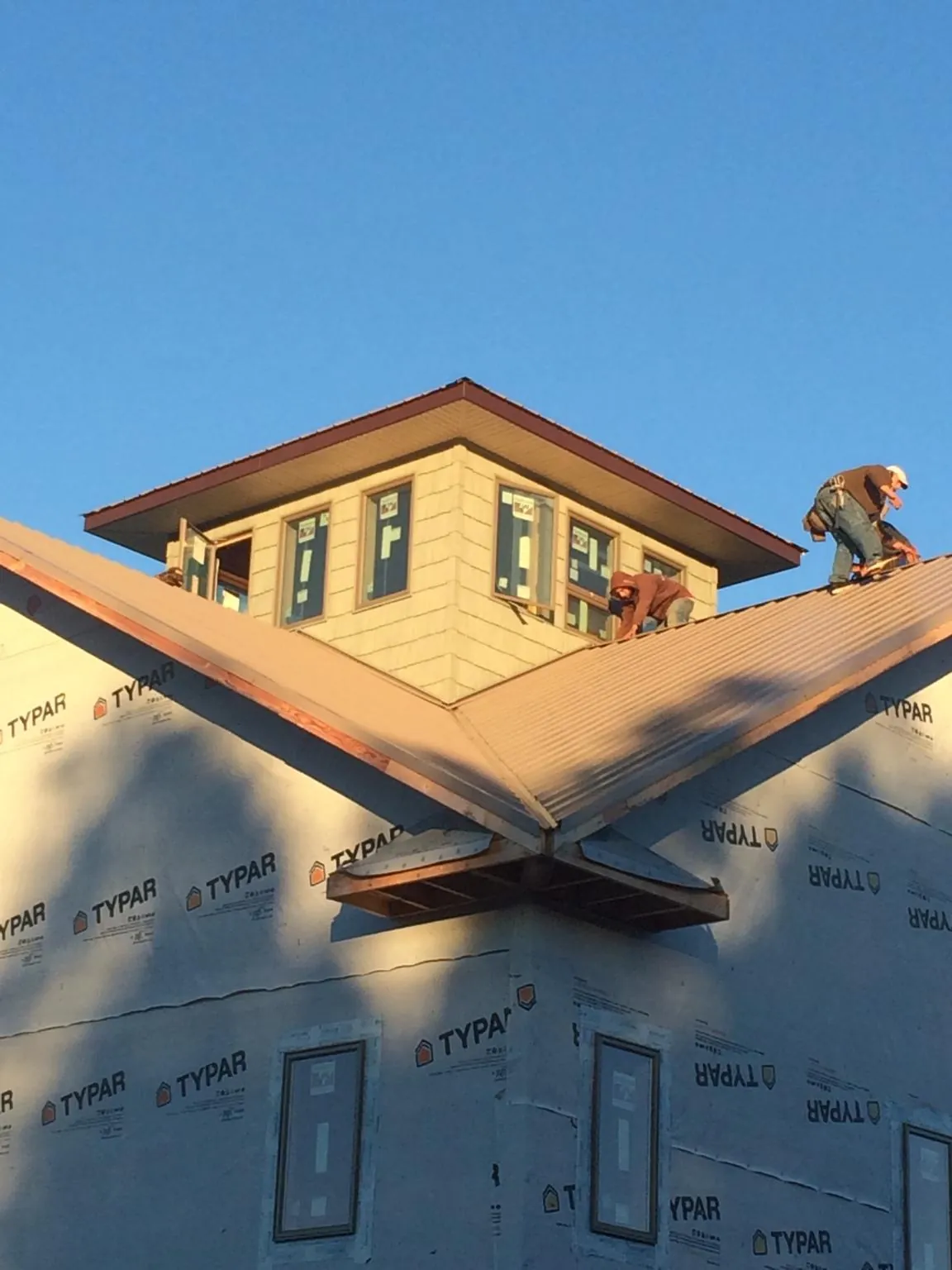 Roofers working around a rooftop cupola on a new metal roof at sunset — Roof Waterproofing in Rock City Falls by Roofing Brothers
